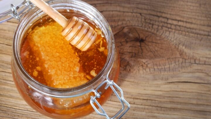 Honey jar with wooden spoon perfect for nourishing chapped lips.