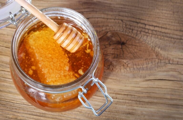 Honey jar with wooden spoon perfect for nourishing chapped lips.