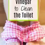 woman sitting on toilet with red gingham pants around feet