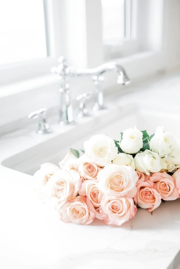 fresh cut white and pink roses in white kitchen sink