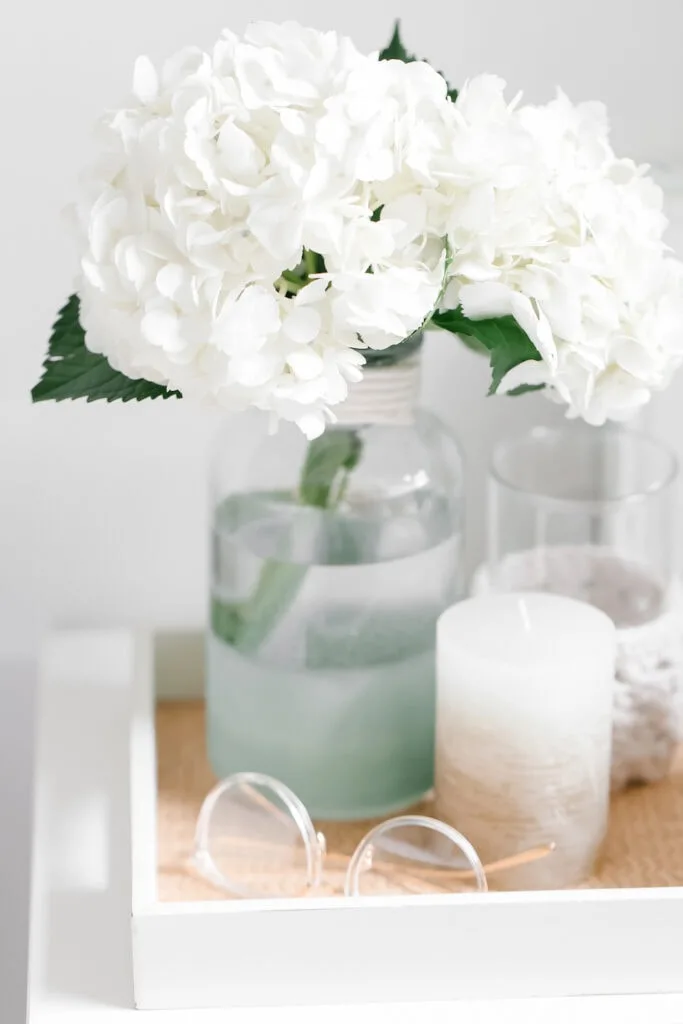 white hydrangeas in glass vase on bedside table 