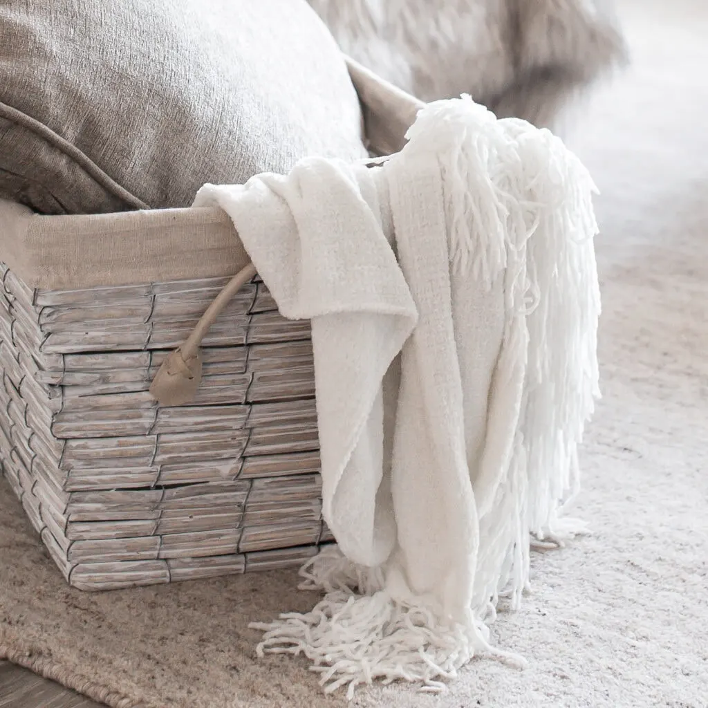 white throw blanket in grey basket with grey pillow