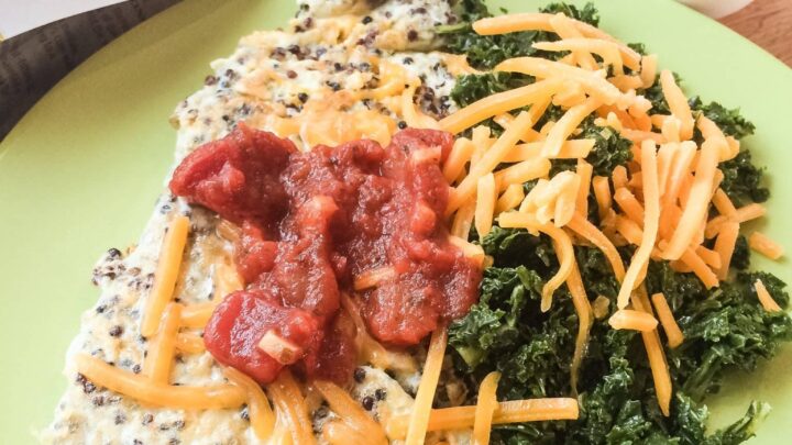 omelette with quinoa on green plate with kale and cheese and eggs in background