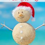sandcastle snowman with red Santa hat on beach