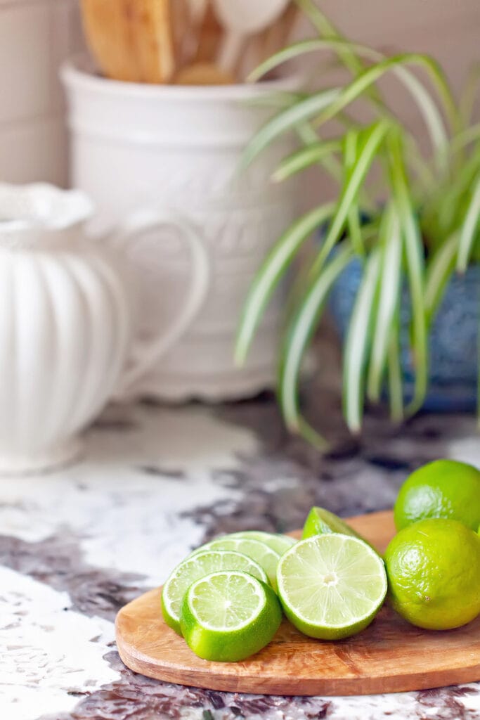 limes on wooden cutting board on kitchen counter