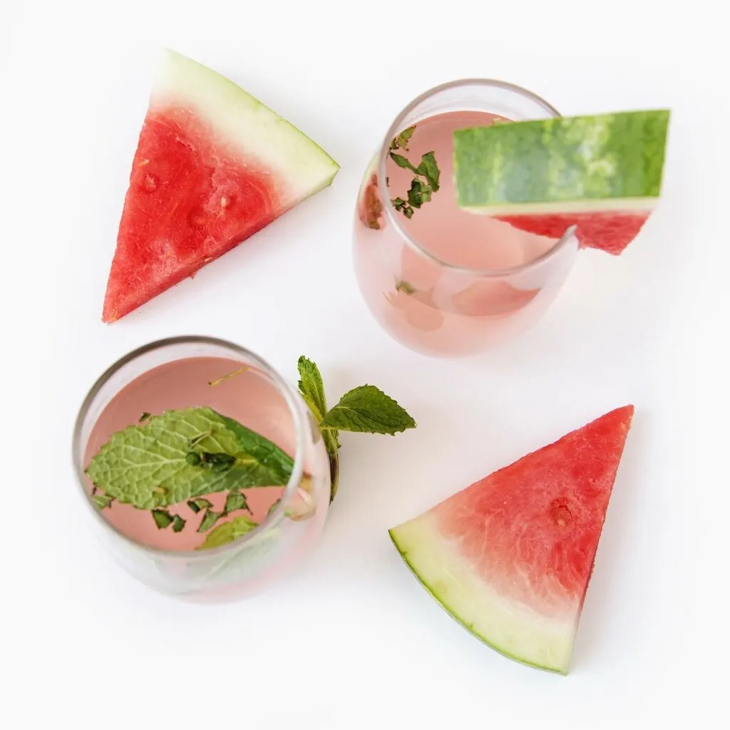 watermelon wedges in pink drinks against white background