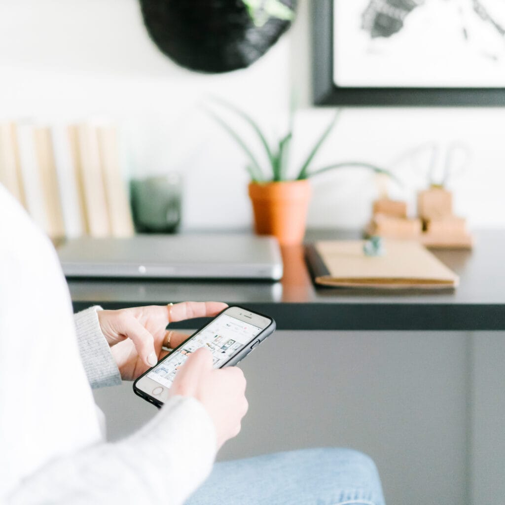 woman sitting at desk scrolling on mobile phone