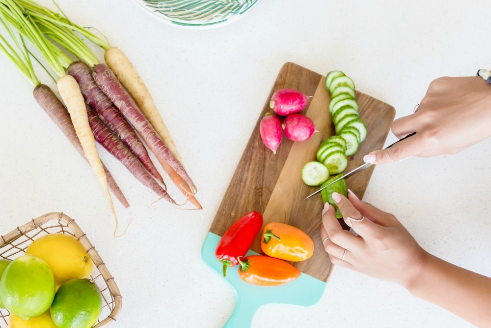 woman cutting vegetables on wood cutting board