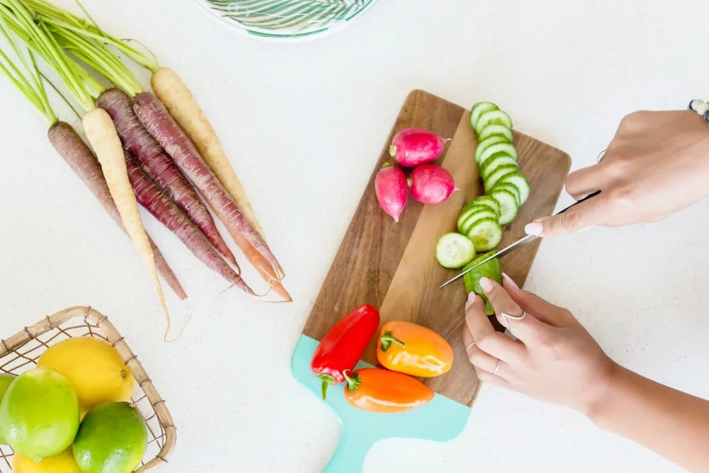 woman cutting vegetables on wood cutting board