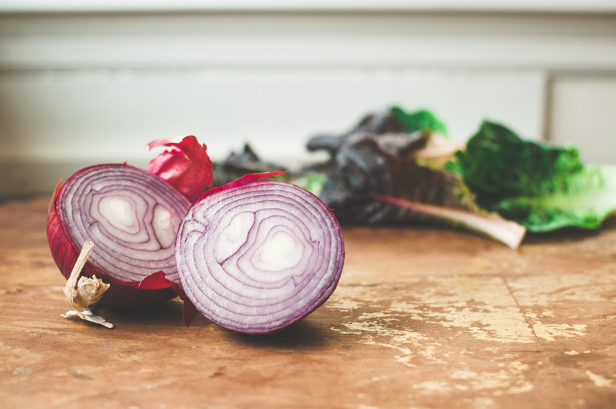 red onion cut in half on wooden cutting board