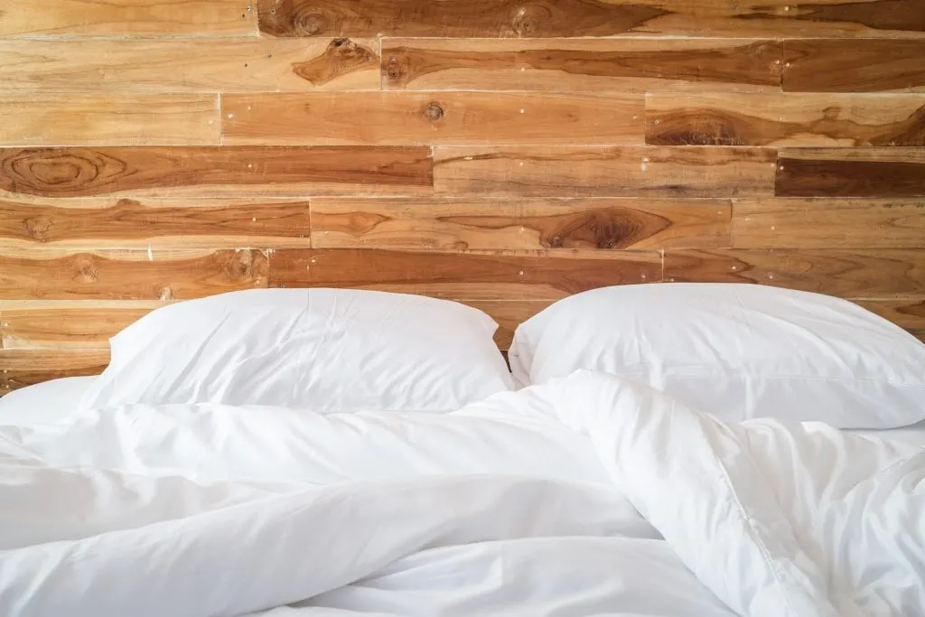 white sheets set against wood headboard