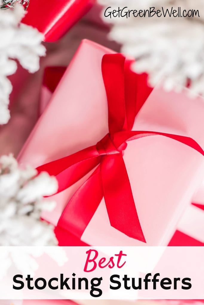 Christmas present wrapped in pink paper with red bow against white tree branches healthy stocking stuffer ideas