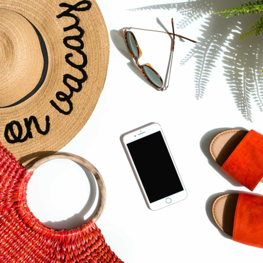 vacation hat on white background with bag phone sunglasses and orange shoes