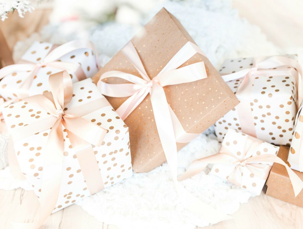 holiday gifts wrapped in brown and white paper with gold polka dots and pink bows holiday gift guide