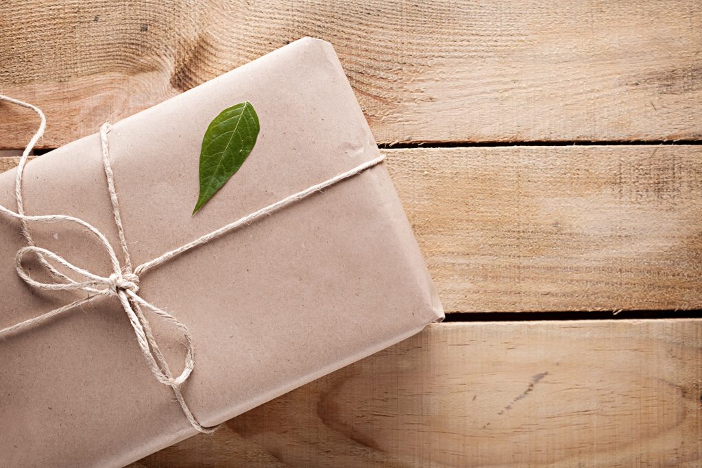 gift box with a green leaf on it on wooden background