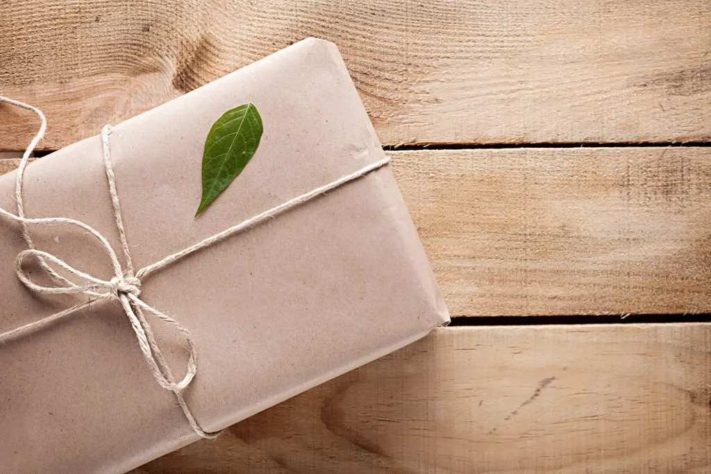 gift box with a green leaf on it on wooden background