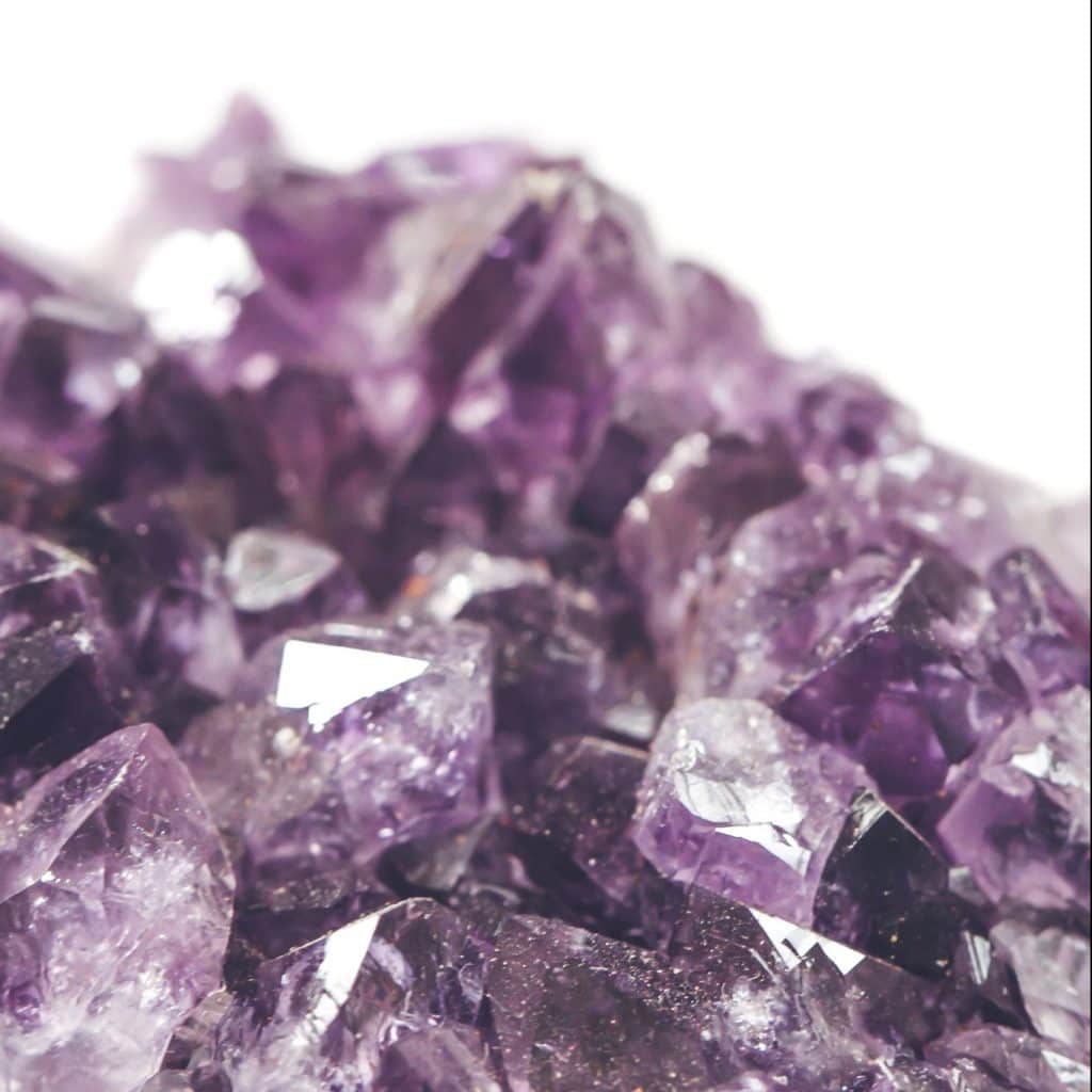 close up of purple crystals against white background