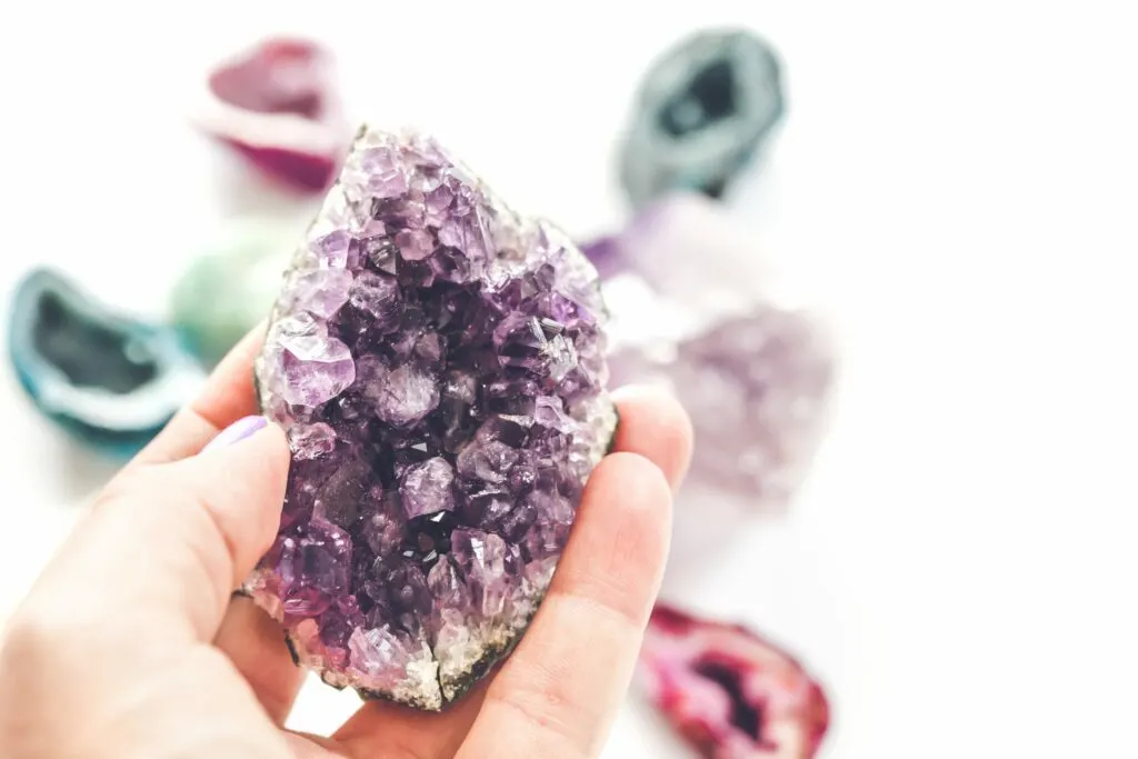 woman holding a purple crystal against colorful geodes