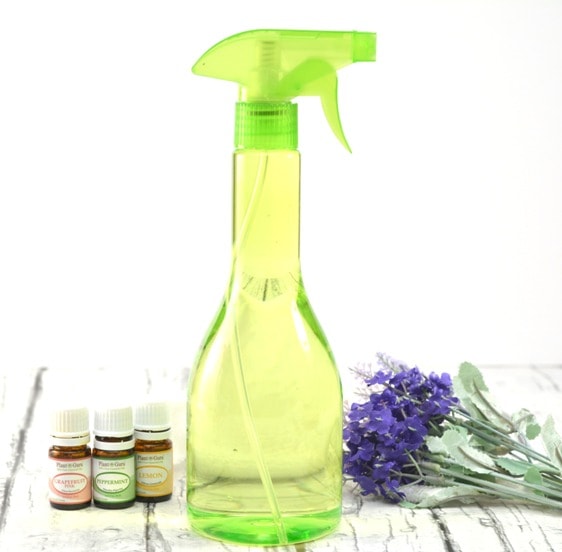 Green Spray Bottle with essential oils and lavender flowers on wooden table