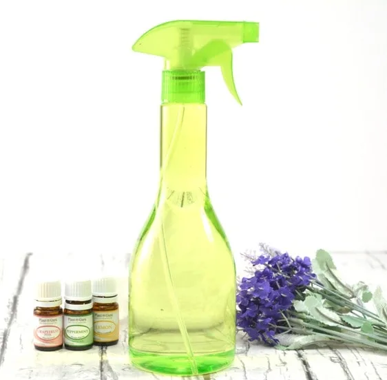 Green Spray Bottle with essential oils and lavender flowers on wooden table