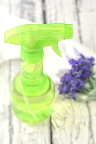 green spray bottle with lavender flowers on wood