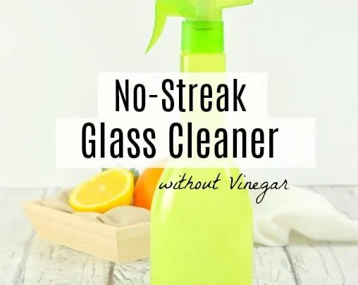 Green spray bottle filled with glass cleaner with crate of oranges behind on the table