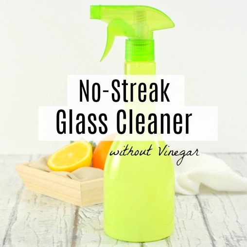 Green spray bottle filled with glass cleaner with crate of oranges behind on the table