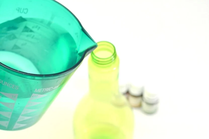 pouring homemade cleaner into a green spray bottle 