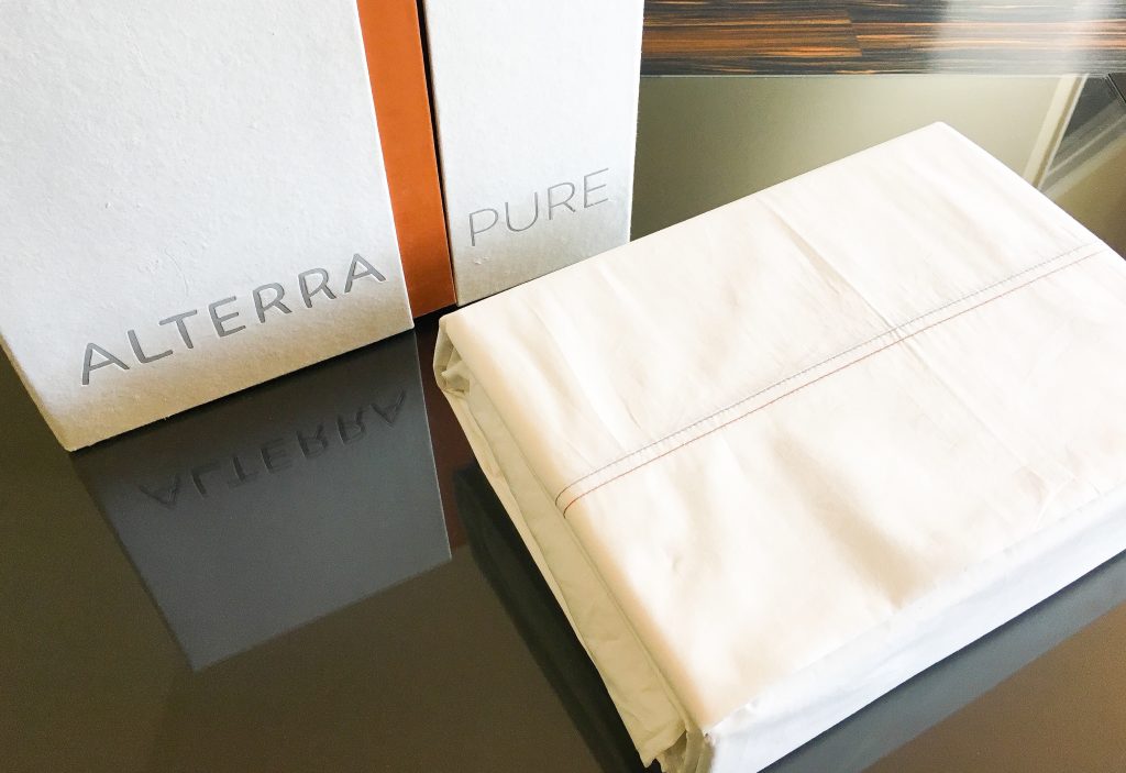 organic off-white cotton sheet set with recycled paper box on a glass table