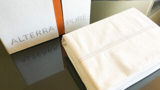 organic off-white cotton sheet set with recycled paper box on a glass table