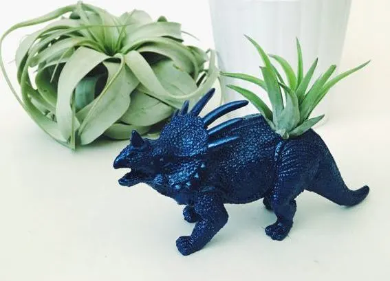 bright metallic blue dinosaur with air plant planted in back with succulent in the background