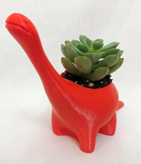 red plastic dinosaur with green suculent plant growing out of it
