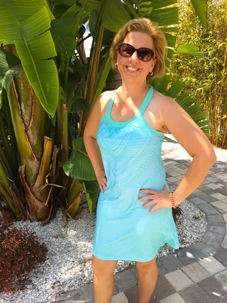woman wearing teal sundress standing by palm tree