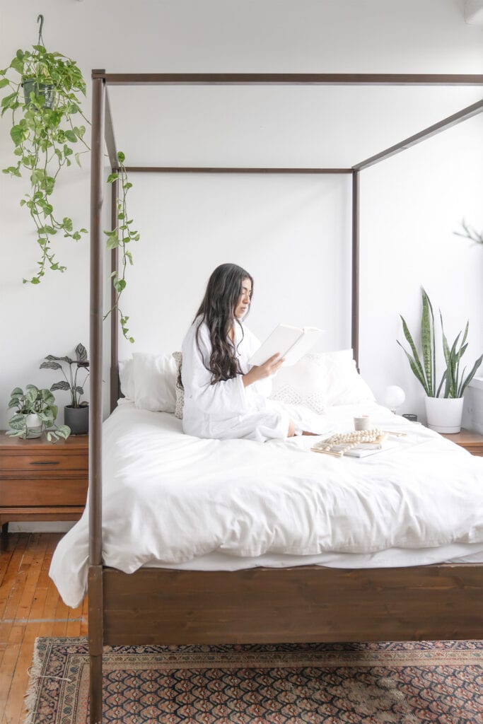 Woman sitting on mattress in bedroom