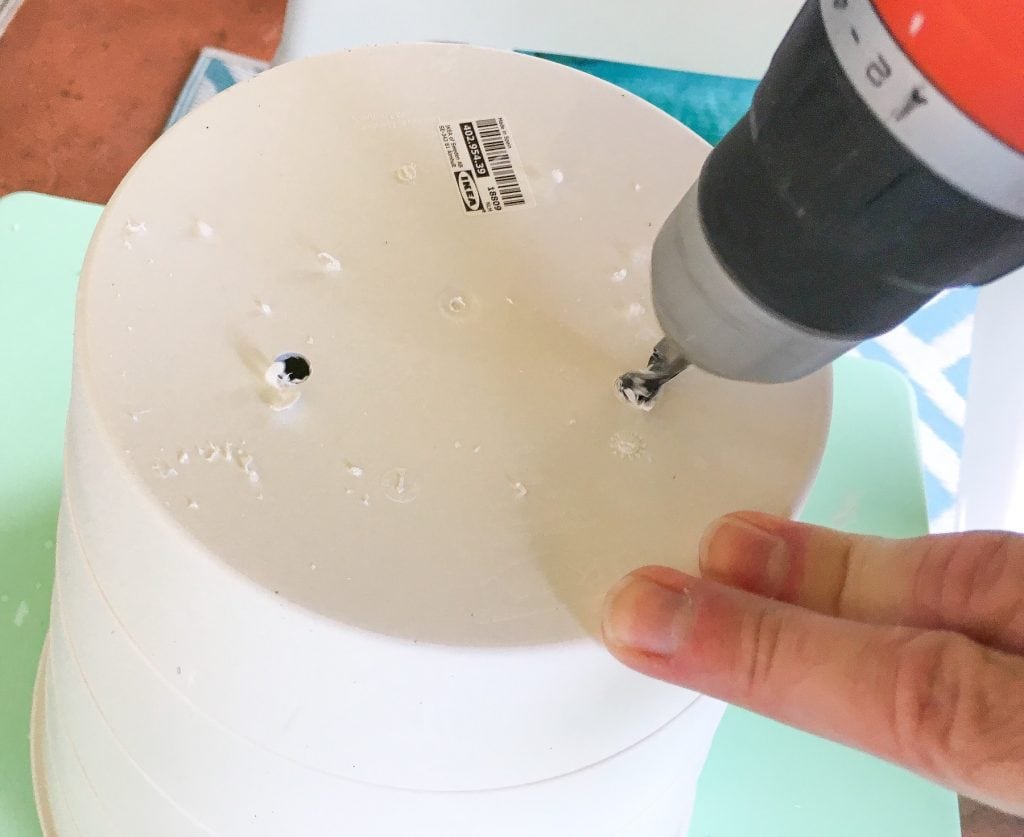 screwdriver drilling holes in a plastic trash can pot