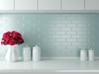 blue backsplash with white counters and white vase filled with pink flowers