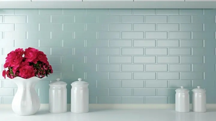 blue backsplash with white counters and white vase filled with pink flowers