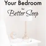 Bedside lamp on night table in bedroom with clock and books on top