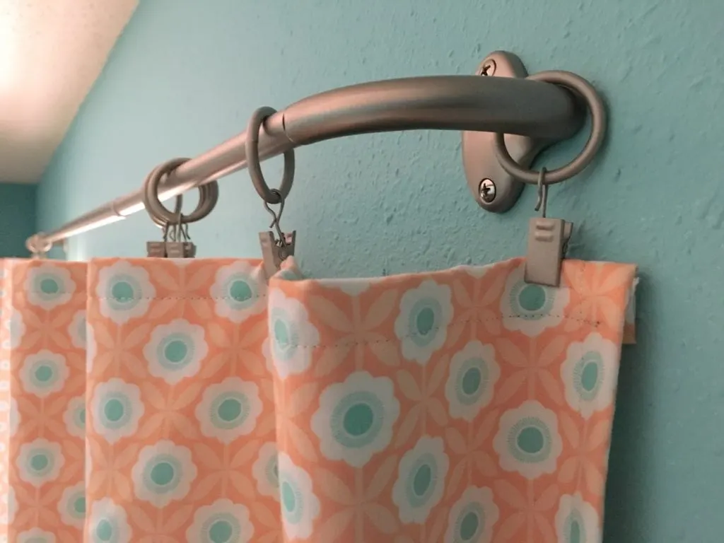 brushed silver metal wrap around curtain rods on blue wall with peach floral curtains