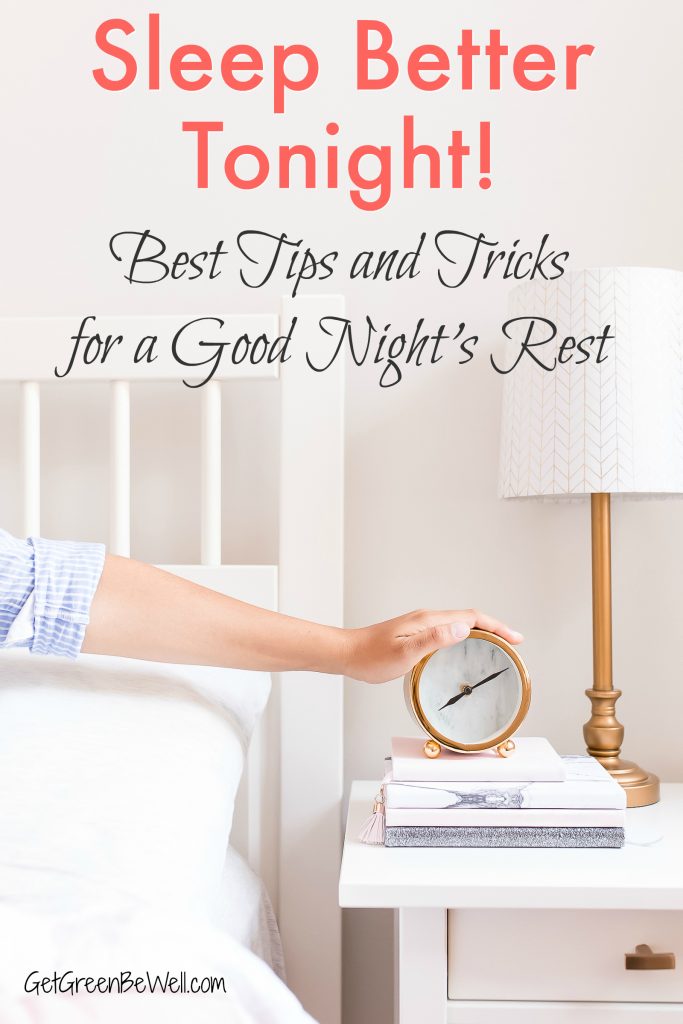 woman with hand on old fashioned bedside clock on night table with lamp against white wall