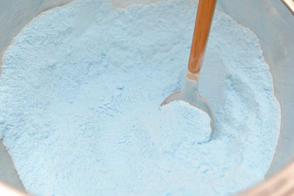 Blue powder in a bowl with a wooden spoon