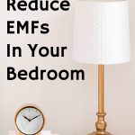 nightstand with gold lamp and battery operated clock on books against pink wall