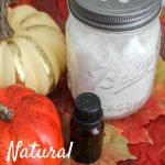 Glass jar with white baking soda against pumpkins, white wood background, fall leaves and essential oil bottle