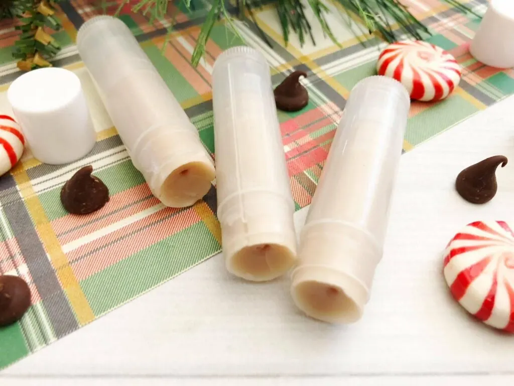 lip balm tubes on table with chocolate chips and peppermint candies