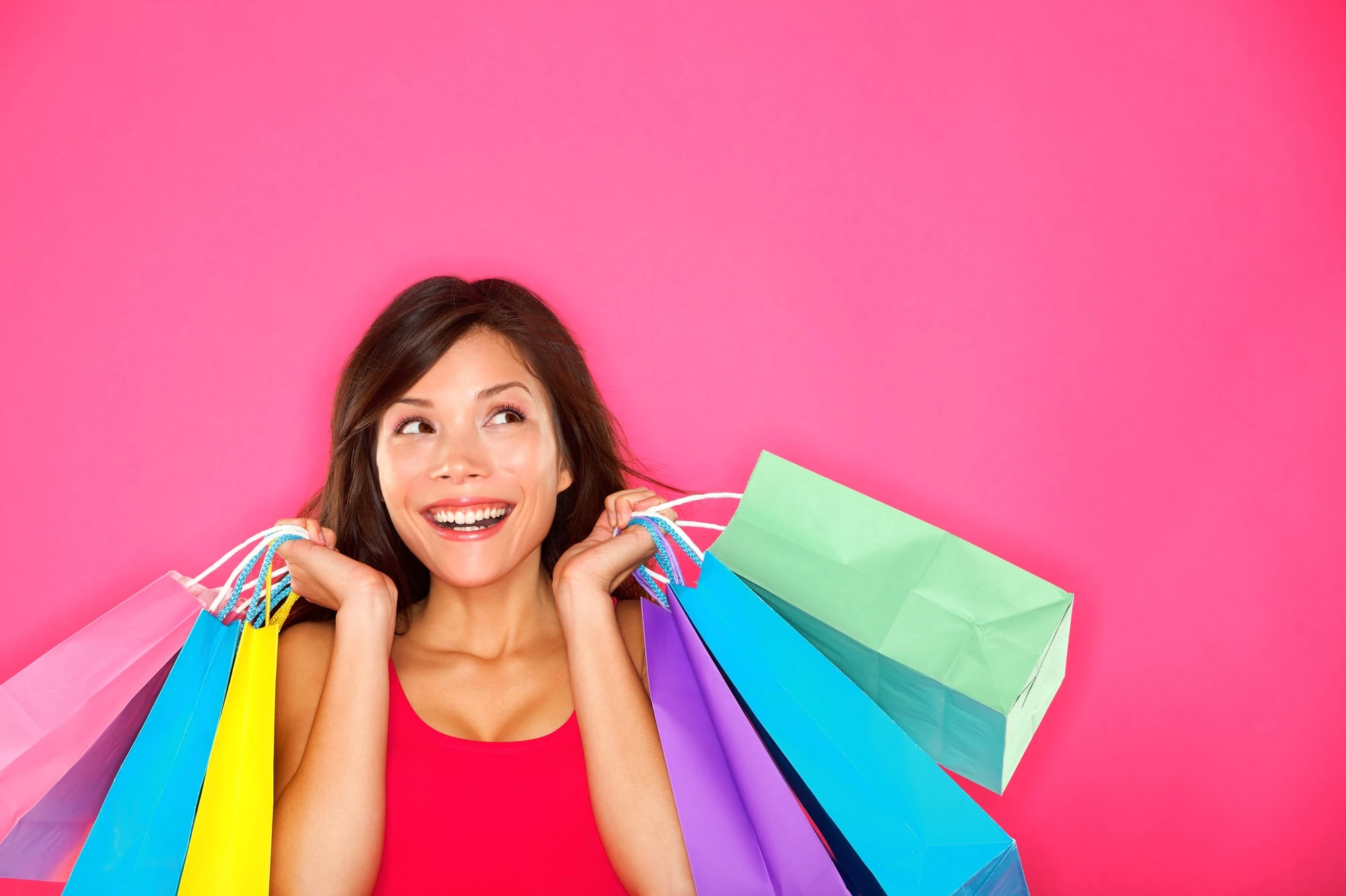 woman with shopping bags against pink background