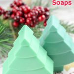 three christmas tree soaps in different shades of green next to pine needles and holly berries