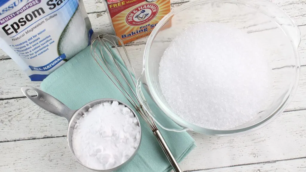 Baking soda box next to glass bowl of nasal decongestant bath salts on white wooden table