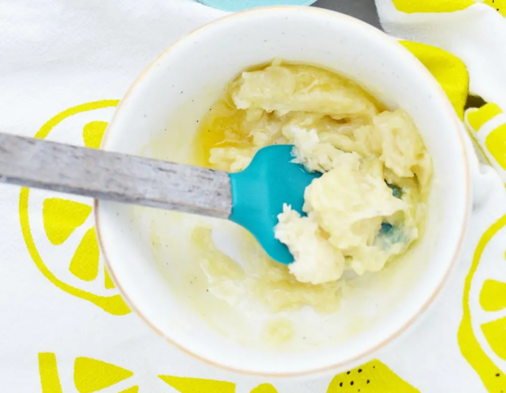 white ceramic bowl with shea butter and lanolin mixed up with blue spatula