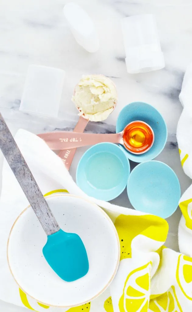 copper measuring spoons with oil and shea butter against blue bowls