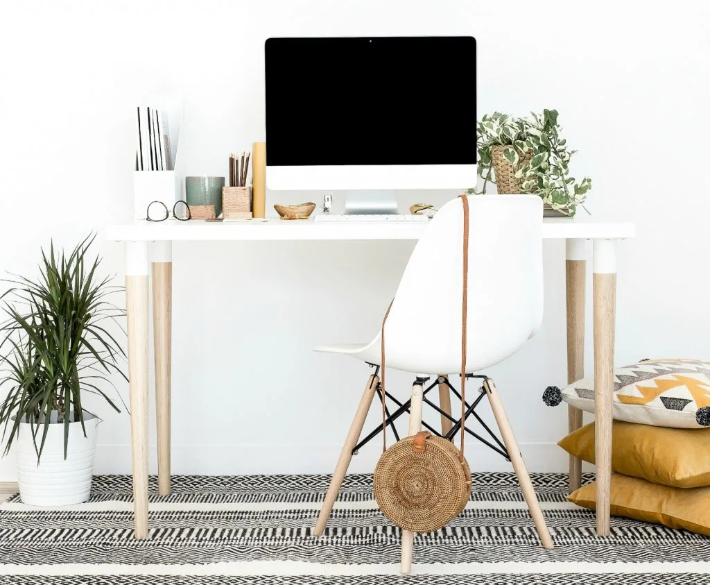 indoor plants on office desk with computer and desk chair against white background